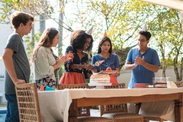 a teen happily cutting the birthday cake in front of a group of friends