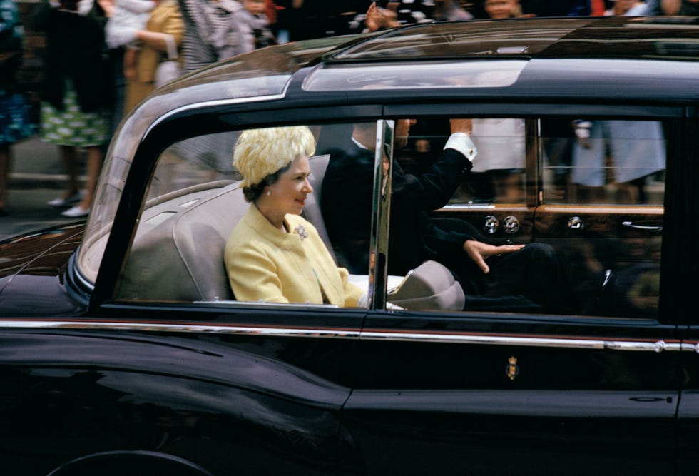 https://i.natgeofe.com/n/29d40a4a-fcbd-4a0b-b5c9-c6d7cd32a502/CV2-001_ARCHIVE_NationalGeographic_153998.jpg Op 9 juli 1965 is koningin Elizabeth II samen met haar man prins Philip de Duke of Edinburgh in een limousine op weg naar Higham Ferrers een stadje buiten Northampton Engeland