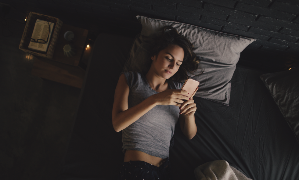 woman lying in bed checking phone