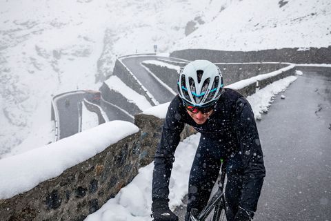 In de sneeuw beklimt een fietser een weg in de Dolomieten waar het weer razendsnel kan omslaan