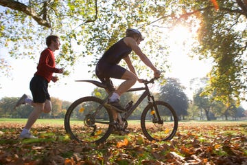 cyclist riding mountain bike with jogger following