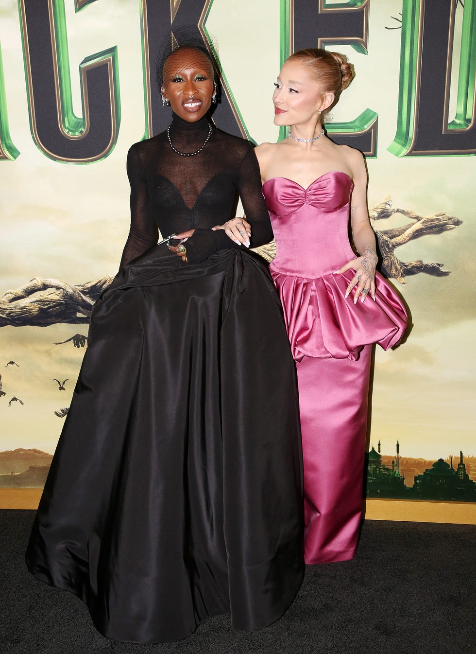 cynthia erivo and ariana grande pose in black and pink gowns at the new york premiere of wicked part 1