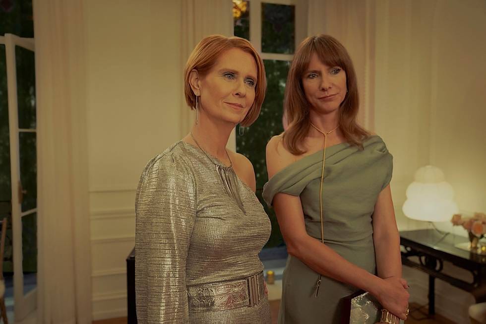 two women in elegant dresses standing together indoors