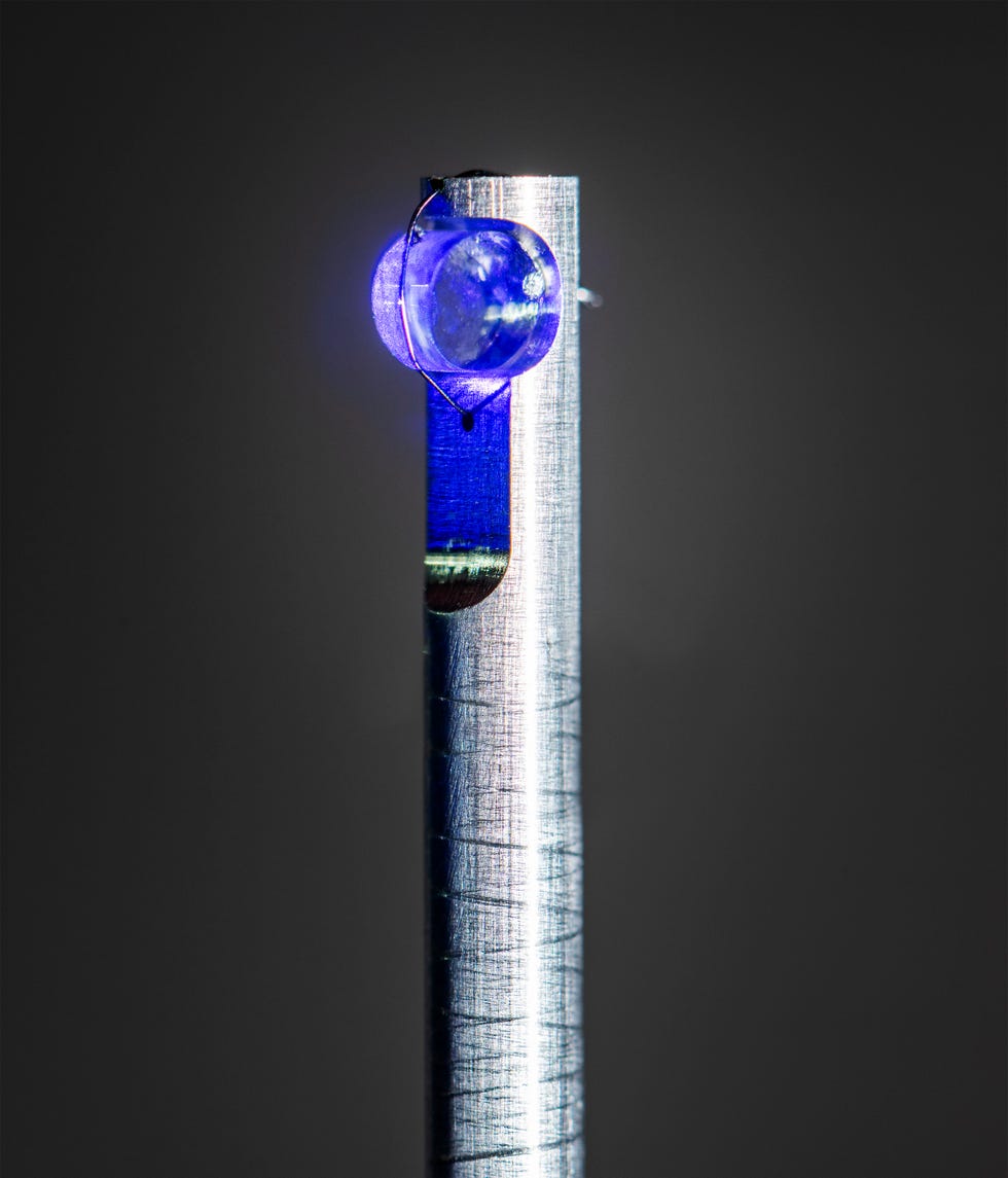 a transparent spherical object and a metallic rod with blue light on top