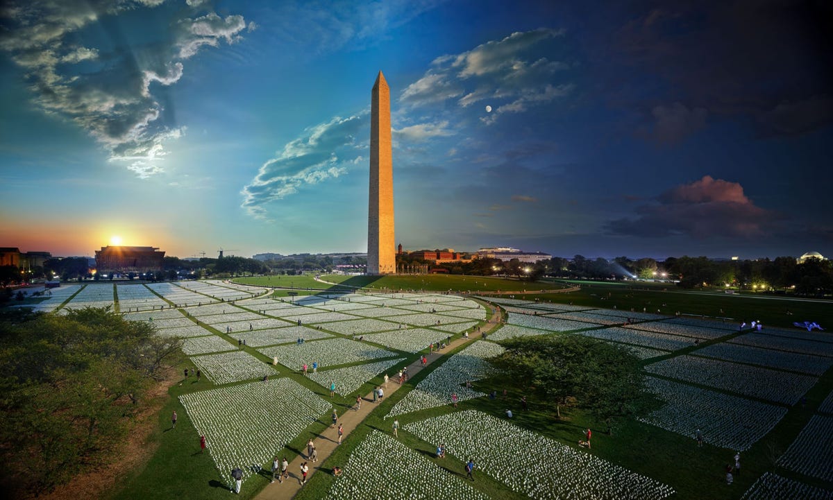 De witte vlaggetjes in het park rond het Washington Monument waren zowel een eerbetoon aan als een symbool van elk leven dat in de Verenigde Staten door COVID19 verloren is gegaan Kunstenares Suzanne Brennan Firstenberg ontwierp de installatie om de enorme omvang van het nationale dodental tot uitdrukking te brengen Maar de vlaggen lieten ook de pijn van afzonderlijke sterfgevallen zien doordat achterblijvers ze versierden met de namen en fotos van hun dierbaren In de drie weken dat de installatie er stond passeerde de VS een grimmige mijlpaal 700000 coronadoden Om deze compositiefoto te maken nam Stephen Wilkes gedurende dertig uur verspreid over drie dagen honderden fotos vanaf hetzelfde standpunt Vervolgens selecteerde hij fotos en voegde deze samen tot deze ene scne Lees meer over de Day to Nighttechniek van Wilkes in het verhaal hieronder