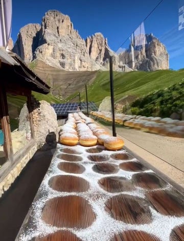 a table displaying freshly made donuts dusted with powdered sugar against a mountainous backdrop