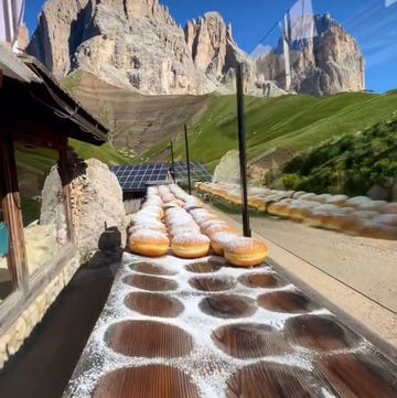 a table displaying freshly made donuts dusted with powdered sugar against a mountainous backdrop a table displaying freshly made donuts dusted with powdered sugar against a mountainous backdrop