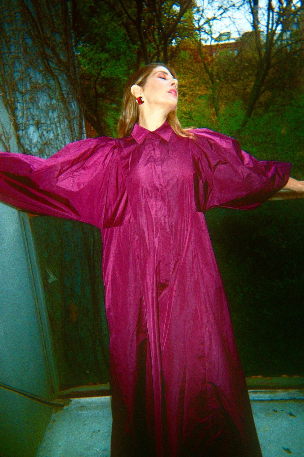 a person wearing a large flowing purple garment with dramatic sleeves standing outside