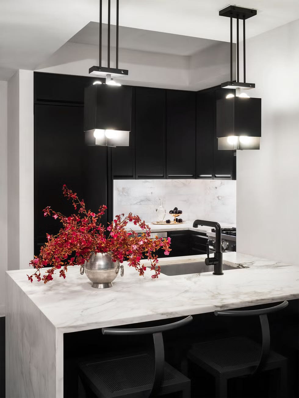 Modern kitchen featuring a marble countertop black cabinetry and decorative floral arrangement
