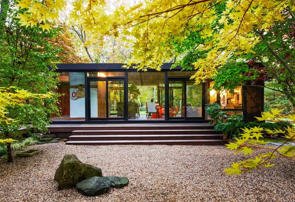 Modern house surrounded by lush greenery with large glass windows.
