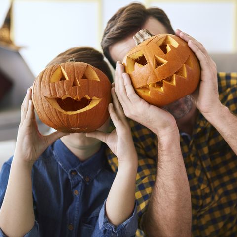 dad and son holding jack o lanterns to their faces