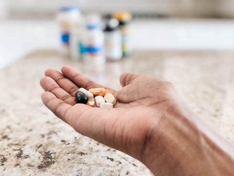 a man with various vitamin supplements in the palm of his hand