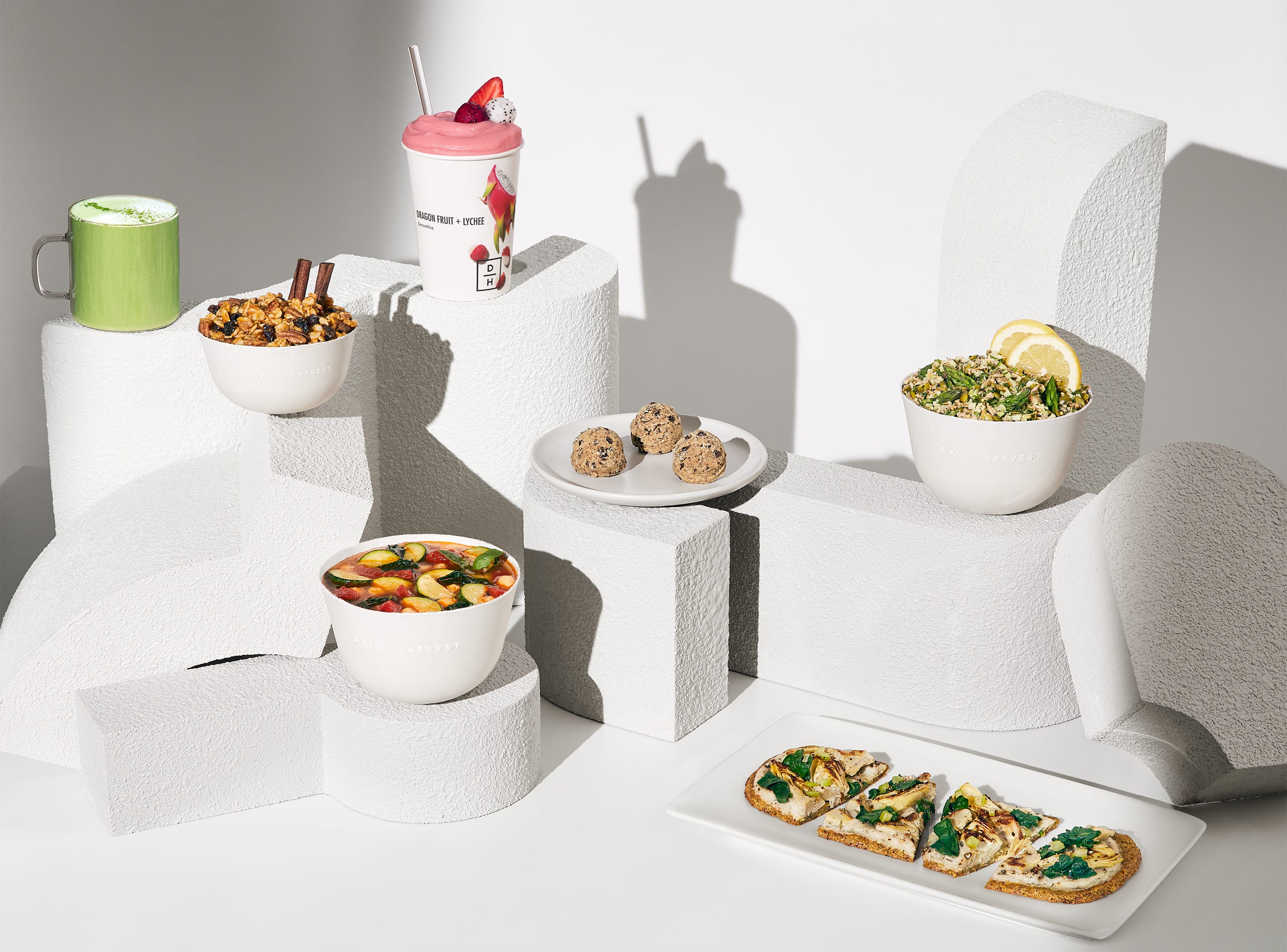 an assortment of prepared vegan meals on a white background from daily harvest, a good housekeeping pick for best healthy meal delivery service