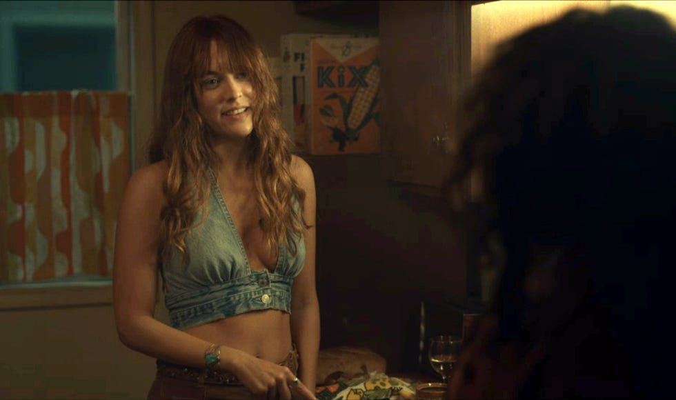 riley keough in a denim bra and tan pants in daisy jones and the six