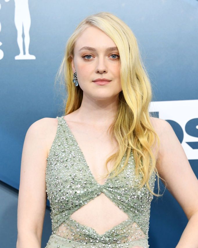 dakota fanning wears a pale green dress with a torso cut out on the red carpet her hair is down in waves and she wears blue earrings