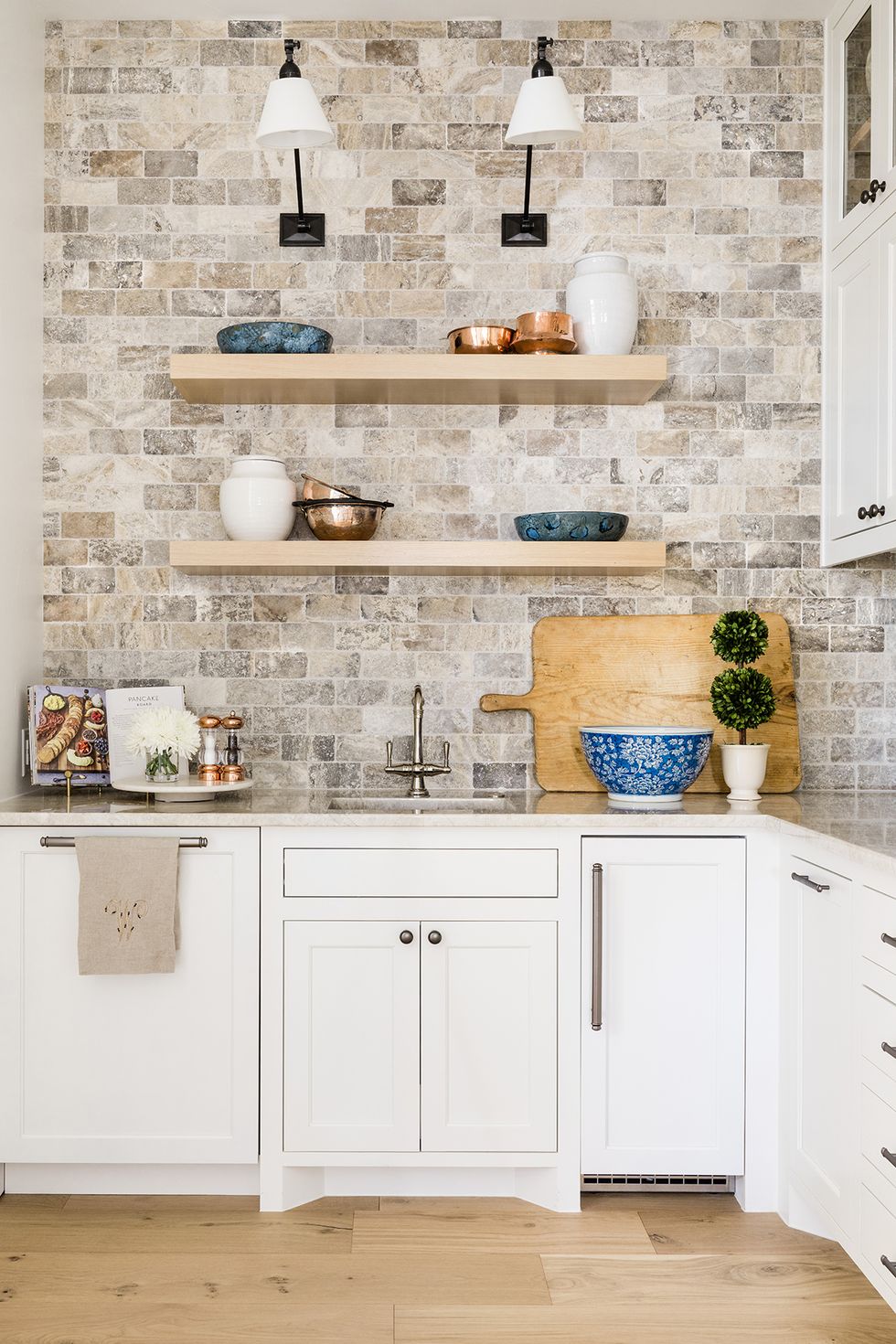 a kitchen with white cabinets and sconces