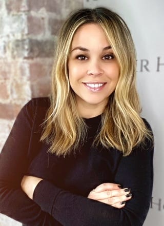person with hands crossed wearing a black top with a blurred face