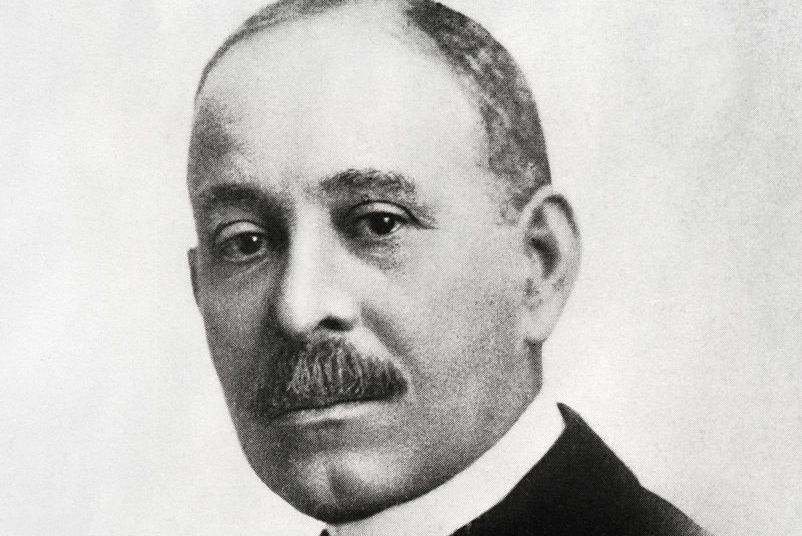 a black and white image of daniel hale williams, looking directly into the camera, wearing a suit and tie
