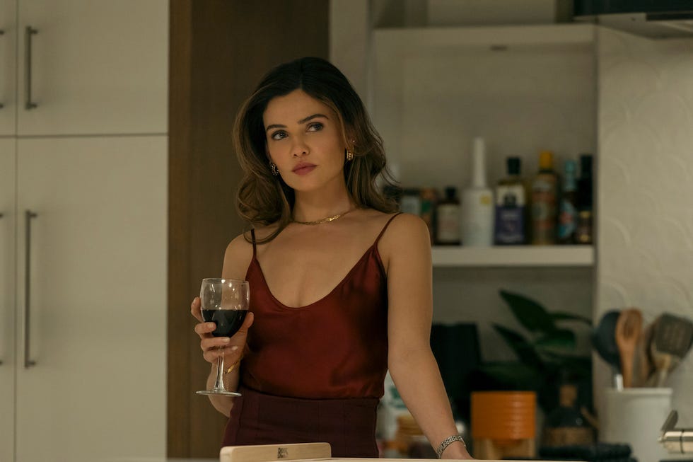 person holding a glass of red wine in a kitchen setting