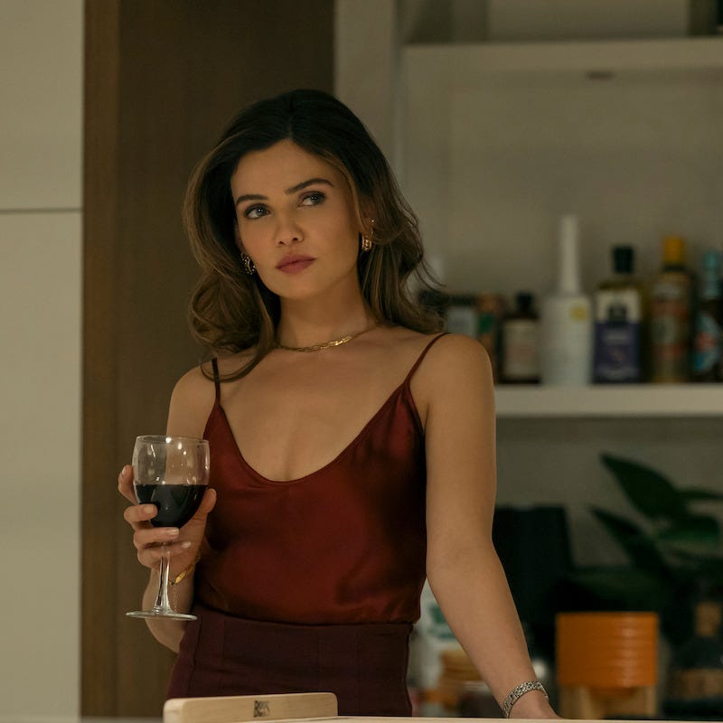 Persona sosteniendo una copa de vino tinto en una cocina.