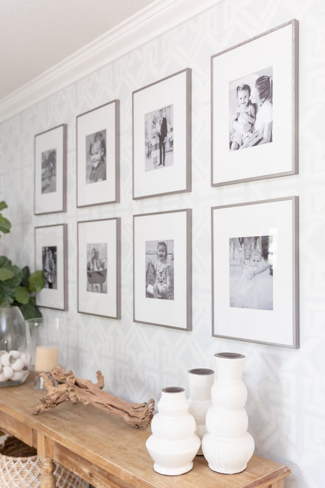 wall adorned with framed black and white photographs and decorative items on a wooden table
