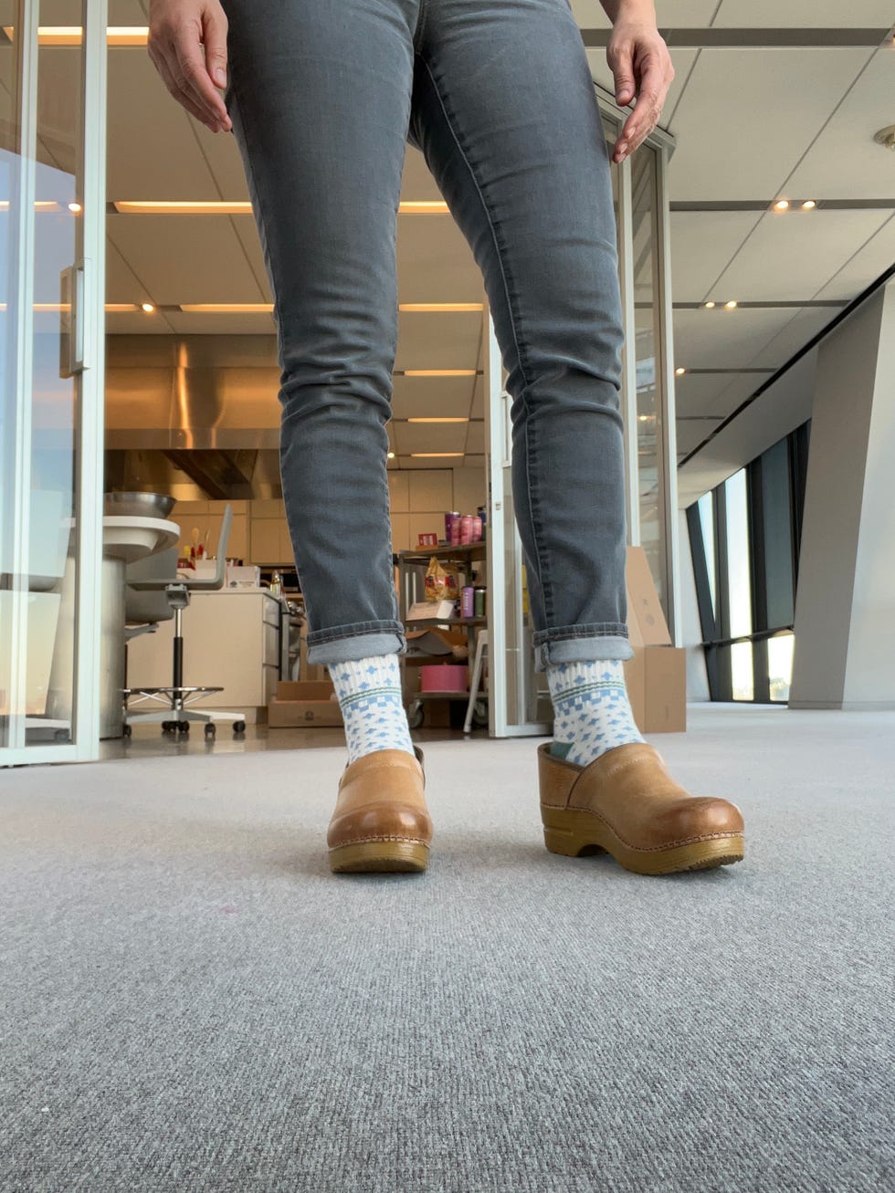 a person wearing tan dansko professional clogs with patterned socks and jeans