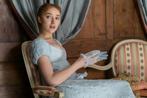 phoebe dynevor as daphne bridgerton in episode 102, seated, wearing a blue, empire waisted dress