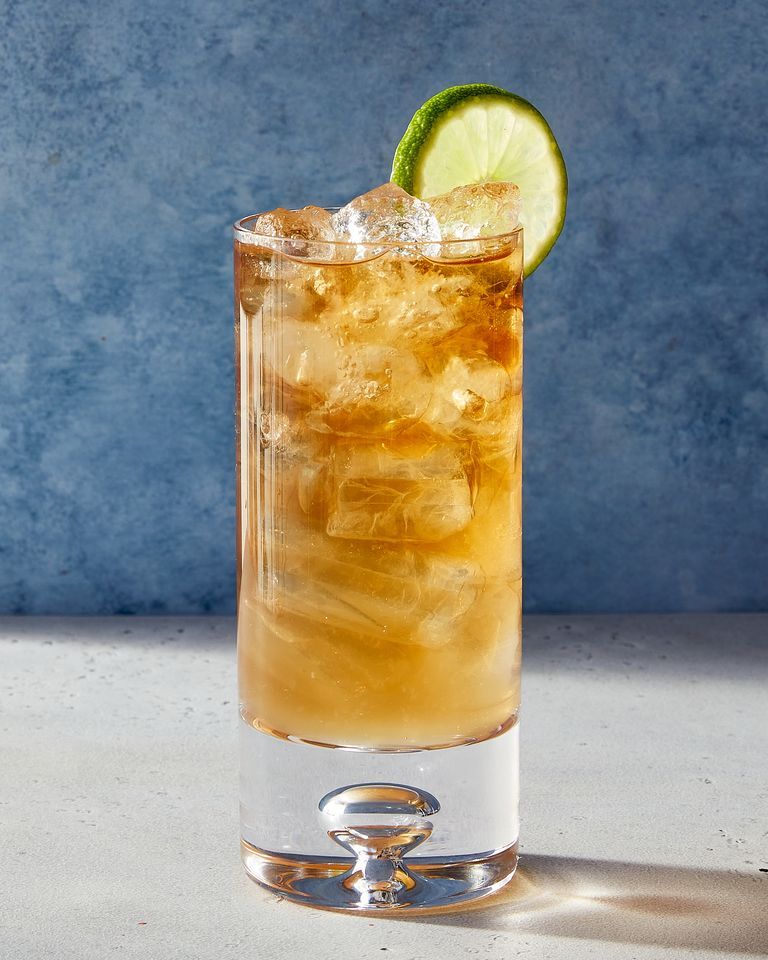 dark and stormy cocktail garnished with lime with a dark blue background