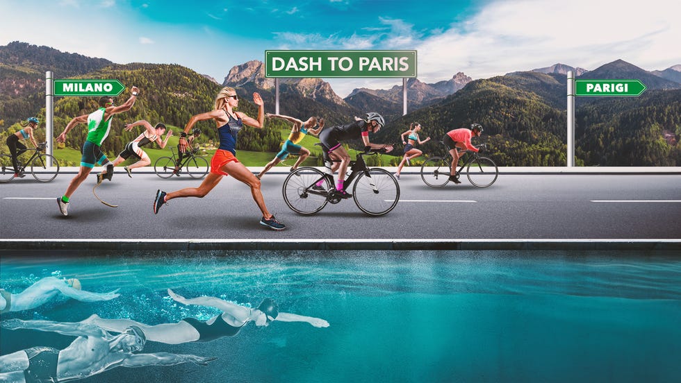 a group of people running on a road with a body of water and mountains in the background