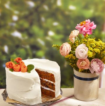 date carrot cake on a stand next to flowers in a vase