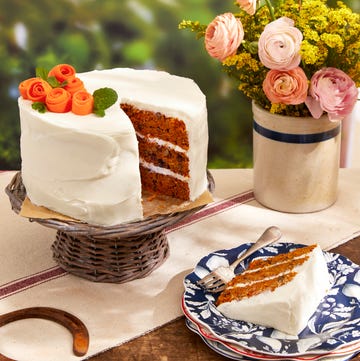 date carrot cake on a stand next to flowers in a vase