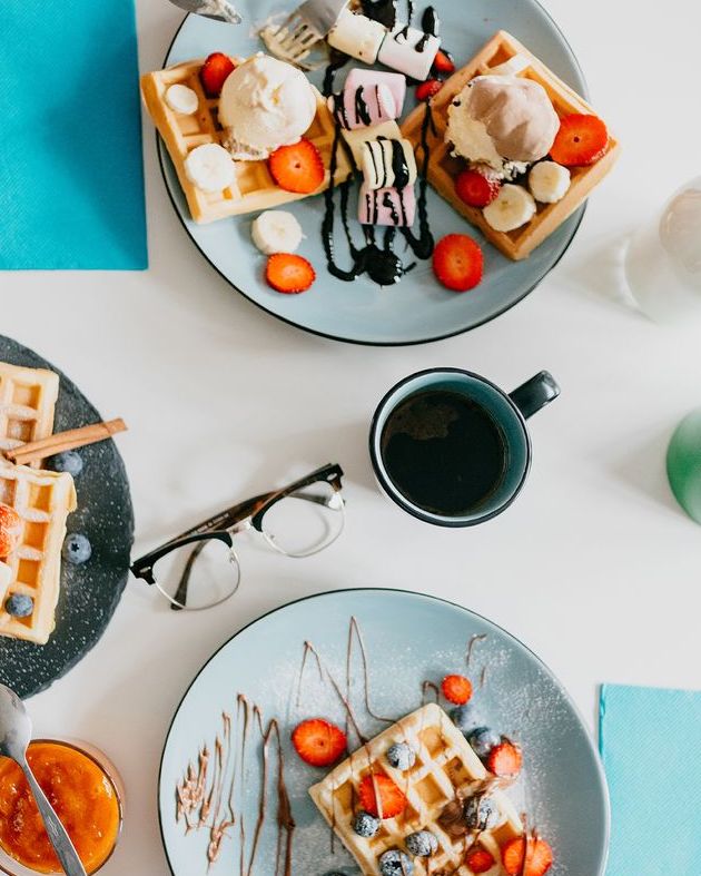 date night ideas with a person cutting bites of waffle on plate with fruit