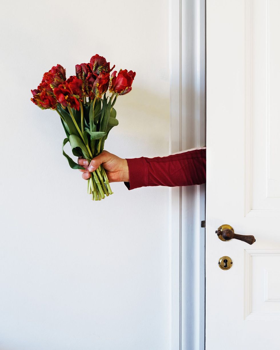 date night ideas person holding bouquet of flowers through door