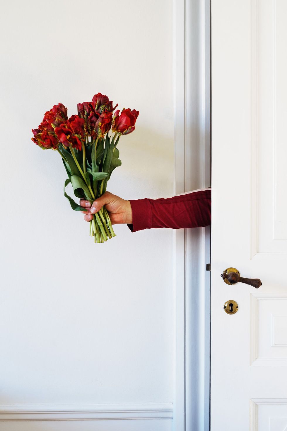 person holding bouquet of flowers through door