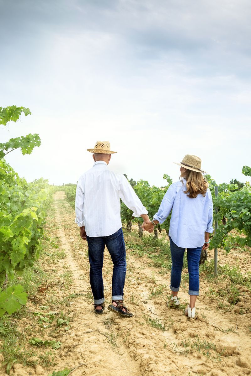 couple holding hands walking through vineyard