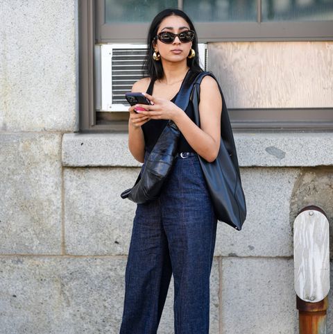 new york, new york september 12 a guest wears sunglasses, a black tank top, blue denim jeans pants, a black leather bag, golden earrings, holds a mobile phone, outside gabriela hearst, during new york fashion week, on september 12, 2023 in new york city photo by edward berthelotgetty images