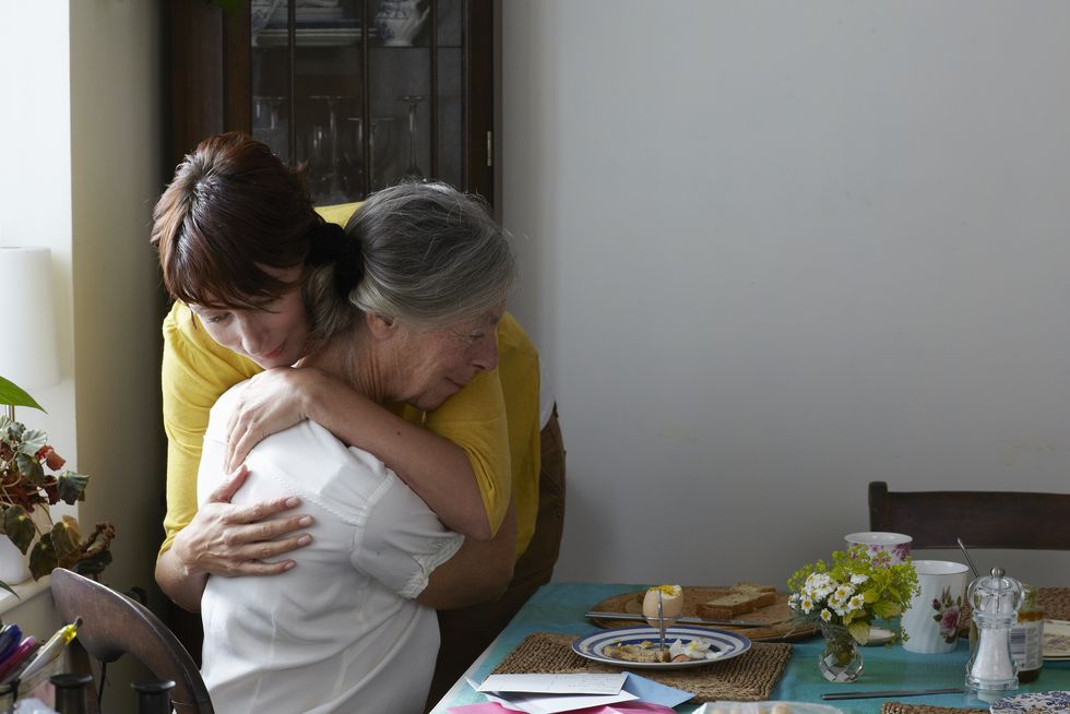 daughter embracing elderly mother in her home