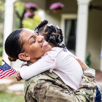 Daughter embracing female U.S. soldier mother in front of home daughter embracing female us soldier mother in front of home