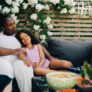 daughter resting by mother at backyard during garden party