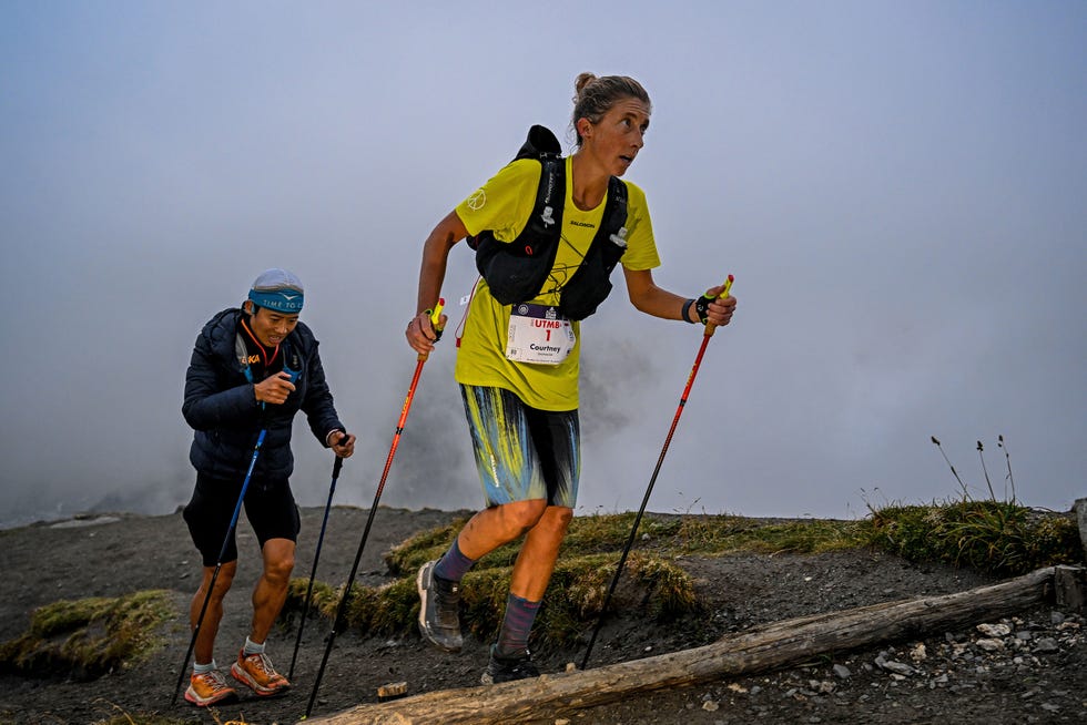 two individuals participating in a mountain trail run with visible hiking poles