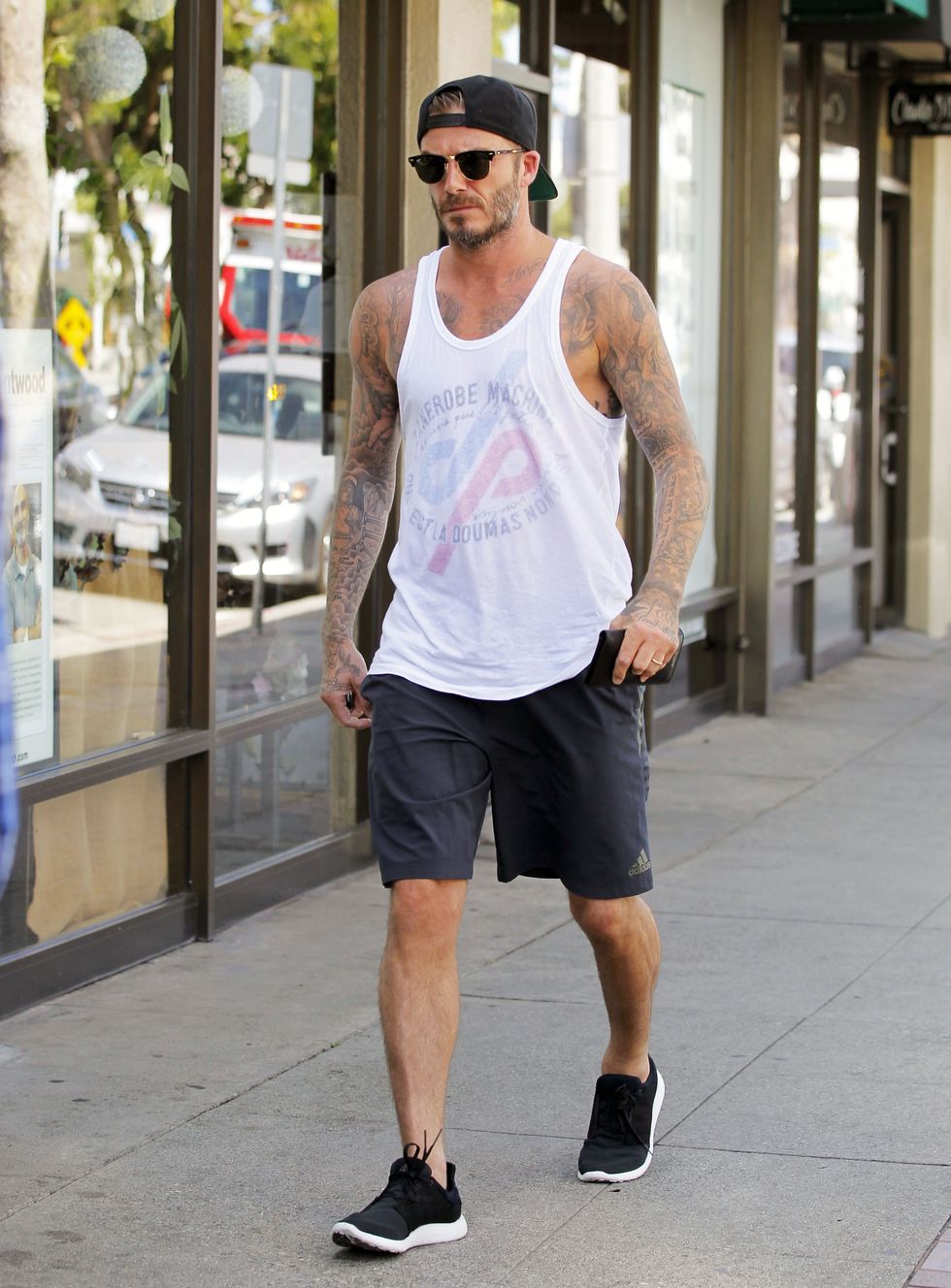muscular male, wearing a tank top, shorts, sneakers, trips and f