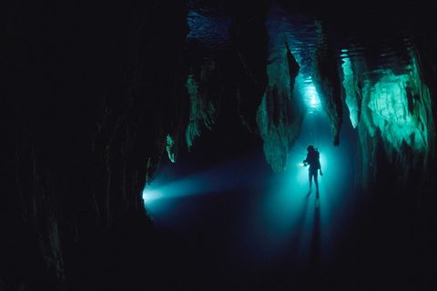 Een silhouet van een duiker in de Chandelier Cave van Palau in Micronesi Duiken in grotten kan gevaar opleveren maar het geeft onderzoekers ook toegang tot unieke omgevingen waar soms historische en archeologische voorwerpen te vinden zijn