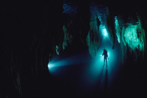 Een silhouet van een duiker in de Chandelier Cave van Palau in Micronesi Duiken in grotten kan gevaar opleveren maar het geeft onderzoekers ook toegang tot unieke omgevingen waar soms historische en archeologische voorwerpen te vinden zijn