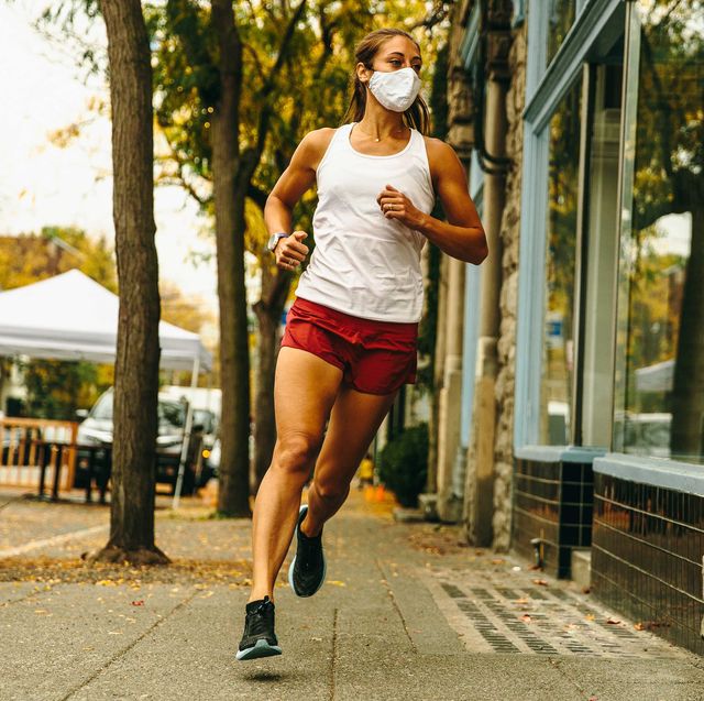 female runner in a white tank top and red shorts rounding the corner