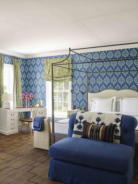 a bedroom with a canopy bed and blue patterned wallpaper