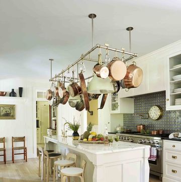 a white kitchen with a large island with a pot rack hanging over it