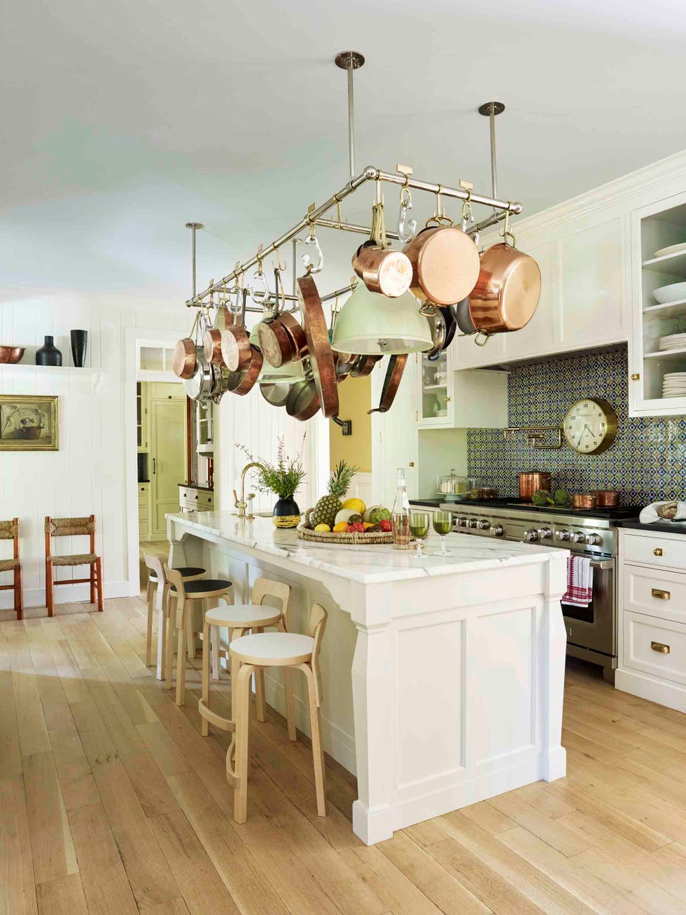 a white kitchen with a large island with a pot rack hanging over it