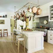 a white kitchen with a large island with a pot rack hanging over it