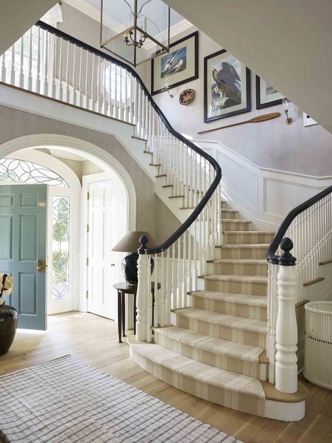a grand staircase with a striped runner and artwork on the walls