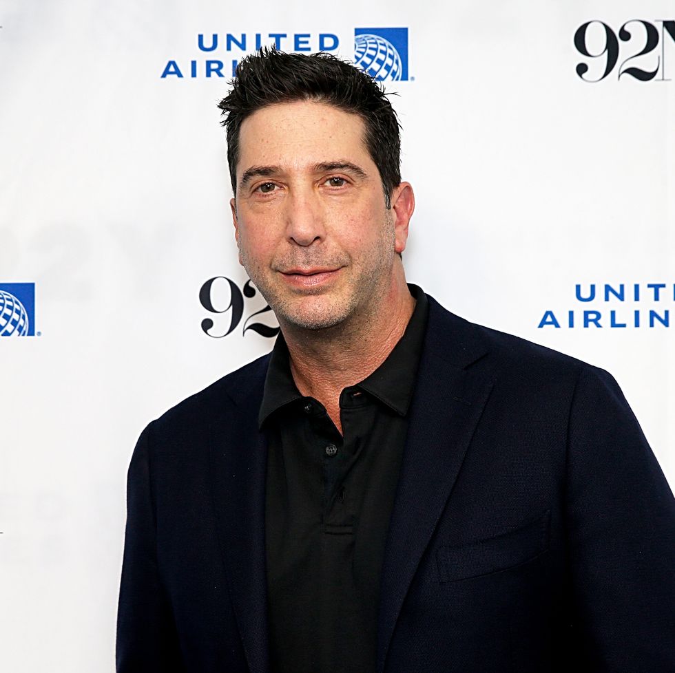 david schwimmer standing for a photo in front of an event red carpet backdrop